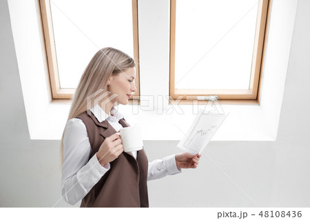 Blonde girl in a business suit works on a computer in a white bright office. 48108436