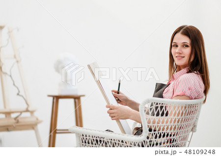 Young woman artist draws a pencil on canvas. Young woman artist draws a pencil on canvas. 48109248