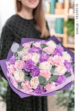 beautiful fresh cut bouquet of mixed flowers in woman hand. the work of the florist at a flower shop beautiful fresh cut bouquet of mixed flowers in woman hand. the work of the florist at a flower shop 48109576