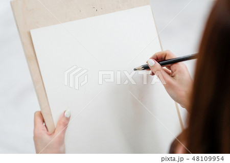 Young woman artist draws a pencil on canvas. Young woman artist draws a pencil on canvas. 48109954