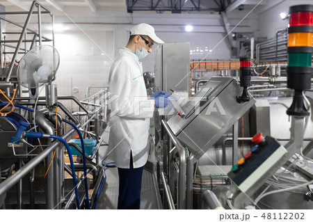 Technologist stands with a tablet near the digital screen at the dairy Plant Technologist stands with a tablet near the digital screen at the dairy Plant 48112202
