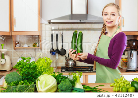 Woman housewife in kitchen with green vegetables 48112487
