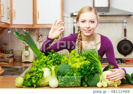 Woman in kitchen with green vegetables 48112489