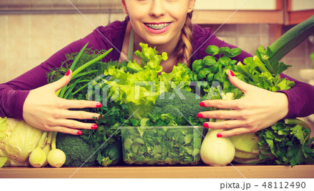 Smiling woman in kitchen with green vegetables 48112490