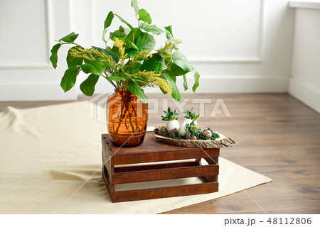 Decor for the Easter holiday, a vase with green leaves and mimosa flowers. Decor for the Easter holiday, a vase with green leaves and mimosa flowers. 48112806