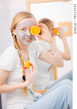 Happy young woman having face mask holding kiwi 48114595