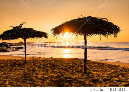 Two beach umbrellas at sunrise on a sandy beach. Tropical island. 48114811