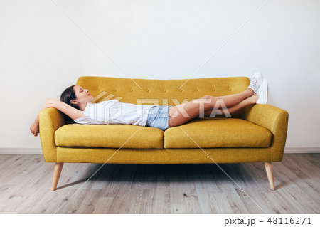 Happy young woman relaxing on couch at home Happy young woman relaxing on couch at home 48116271