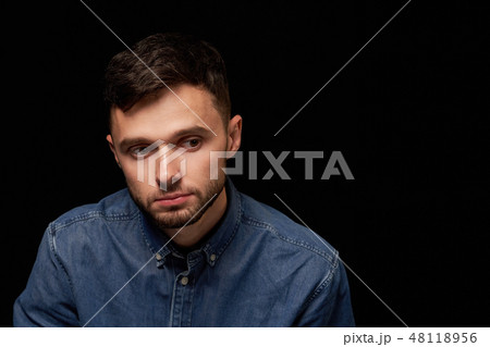 Man in denim shirt looking looking down with thoughtful 48118956