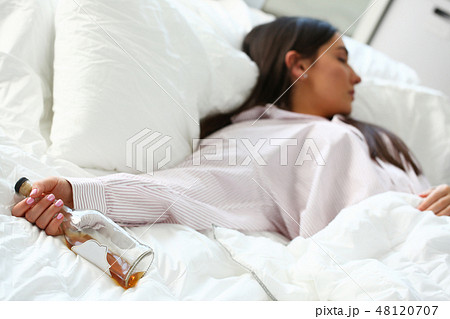 Young woman lying in bed deadly drunken 48120707