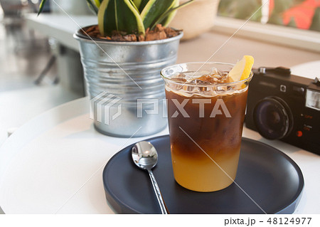 Glass of coffee and camera on the table in cafe. 48124977