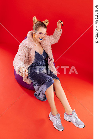 Fashionable woman wearing grey sneakers sitting on comfy chair Fashionable woman wearing grey sneakers sitting on comfy chair 48125806