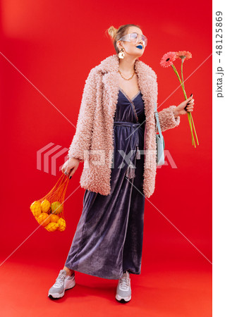 Fashionable woman coming home with bag of fruits and flowers Fashionable woman coming home with bag of fruits and flowers 48125869