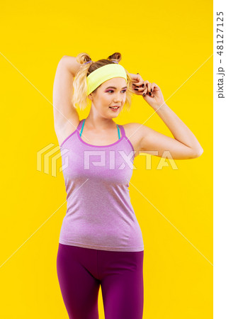 Woman wearing yellow head band stretching muscles 48127125
