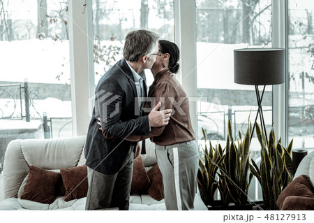 Tall grey-haired handsome man in a dark jacket hugging his business partner 48127913