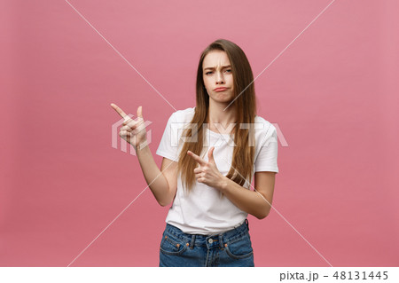 Closeup of serious strict young woman wears white shirt looks stressed and pointing up with finger Closeup of serious strict young woman wears white shirt looks stressed and pointing up with finger 48131445
