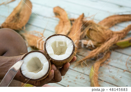 Halved inner coconut in asian man's hands 48145683