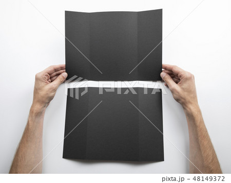 Mens hands holding black booklet 48149372