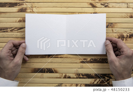Mens hands holding white booklet Mens hands holding white booklet 48150233
