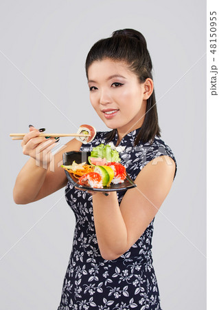 Young beautiful asian woman eating sushi with chopsticks, 48150955