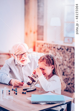 Intriguing girl considering microelement in microscope at home Intriguing girl considering microelement in microscope at home 48155064