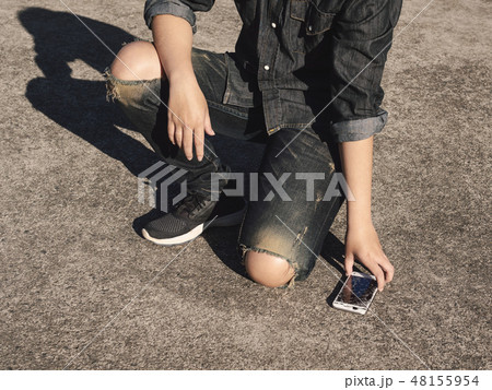 Man picking broken smartphone from floor 48155954