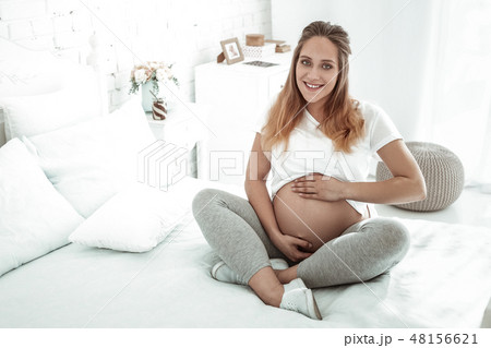 Smiling future mother lifting her t-shirt and presenting round stomach Smiling future mother lifting her t-shirt and presenting round stomach 48156621