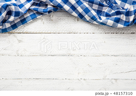 Blue checkered kitchen tablecloth on wooden table. 48157310
