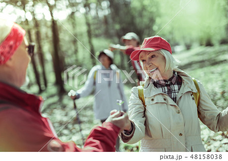 Smiling elderly woman walking in the forest with her partner Smiling elderly woman walking in the forest with her partner 48158038