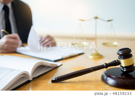 Male lawyer working with contract papers and reading law book in 48159233