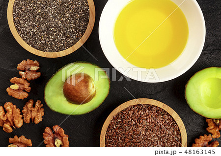An overhead photo of the ingredients of a healthy vegan omega 3 diet. Avocado, nuts, chia and flax 48163145
