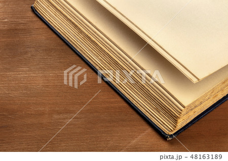 The pages of a thick old book on a dark rustic background with a place for text 48163189