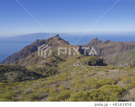 view on asfalt road to village Masca with green hills, sharp mountain peaks, sea horizon and clear view on asfalt road to village Masca with green hills, sharp mountain peaks, sea horizon and clear 48163958