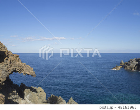 sea horizon with sharp rocks and cliffs in forward, creal blue sky background 48163963