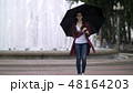 girl with an umbrella in the park on a background of a fountain 48164203