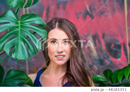 Close up portrait of a young brunette lady, wearing blue dress. The girl posing, looking at the 48165351