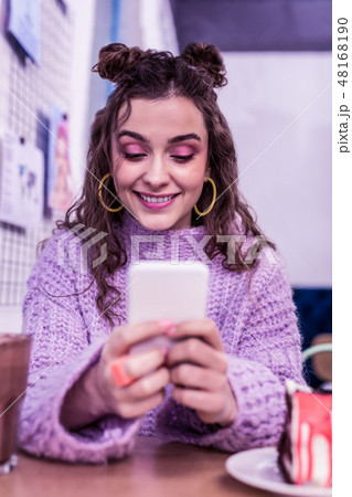 Pretty little lady with two buns and purple make up looking on the screen 48168190