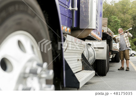Truck driver working on semi-truck 48175035
