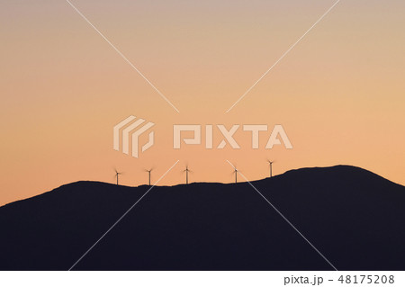Silhouette of wind turbines on hill at sunset Silhouette of wind turbines on hill at sunset 48175208