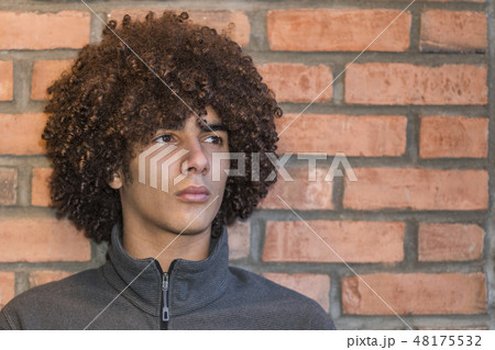 Teenage boy with afro by brick wall 48175532