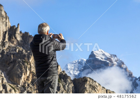 Man taking photograph with smartphone at Giau Pass in the Dolomites 48175562