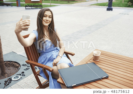 Woman taking selfie at outdoor cafe table Woman taking selfie at outdoor cafe table 48175612