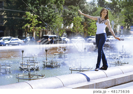 Woman walking by water fountain Woman walking by water fountain 48175636