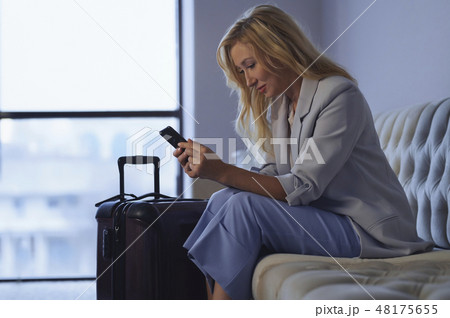 Businesswoman with smartphone and luggage in airport lounge 48175655