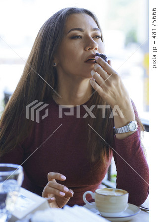 Woman eating chocolate at cafe Woman eating chocolate at cafe 48175666