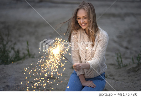 Young woman with sparkler on beach Young woman with sparkler on beach 48175730