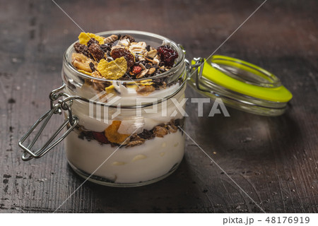 Glass full of white yogurt and muesli on dark wooden board Glass full of white yogurt and muesli on dark wooden board 48176919