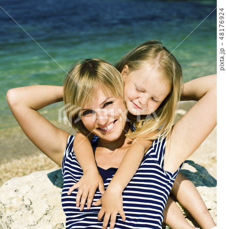mother with daughter at sea cost together, happy real family smiling looking to horizont, lifestyle 48176924