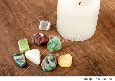Semiprecious gemstones on a dark wooden background with candle and copy space 48178178