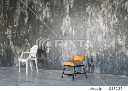 Two chairs against the gray concrete wall. Room in loft style. Wooden floor. Daylight. Free space Two chairs against the gray concrete wall. Room in loft style. Wooden floor. Daylight. Free space 48182824